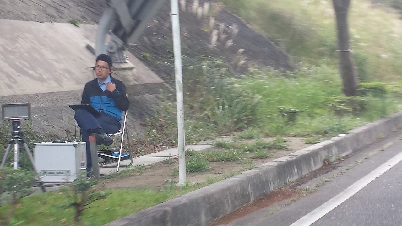 ここまで近づくと分かりますが、ここでレーダーに気付いたって「時既に遅し！」です。無線で「はい“わ”ナンバーの白のカローラ」とこの先に控えている取り締まり軍団に伝えられ、手持ちの「止まれ」の旗に止められて、あえなく御用となる訳です。 〜 画像3