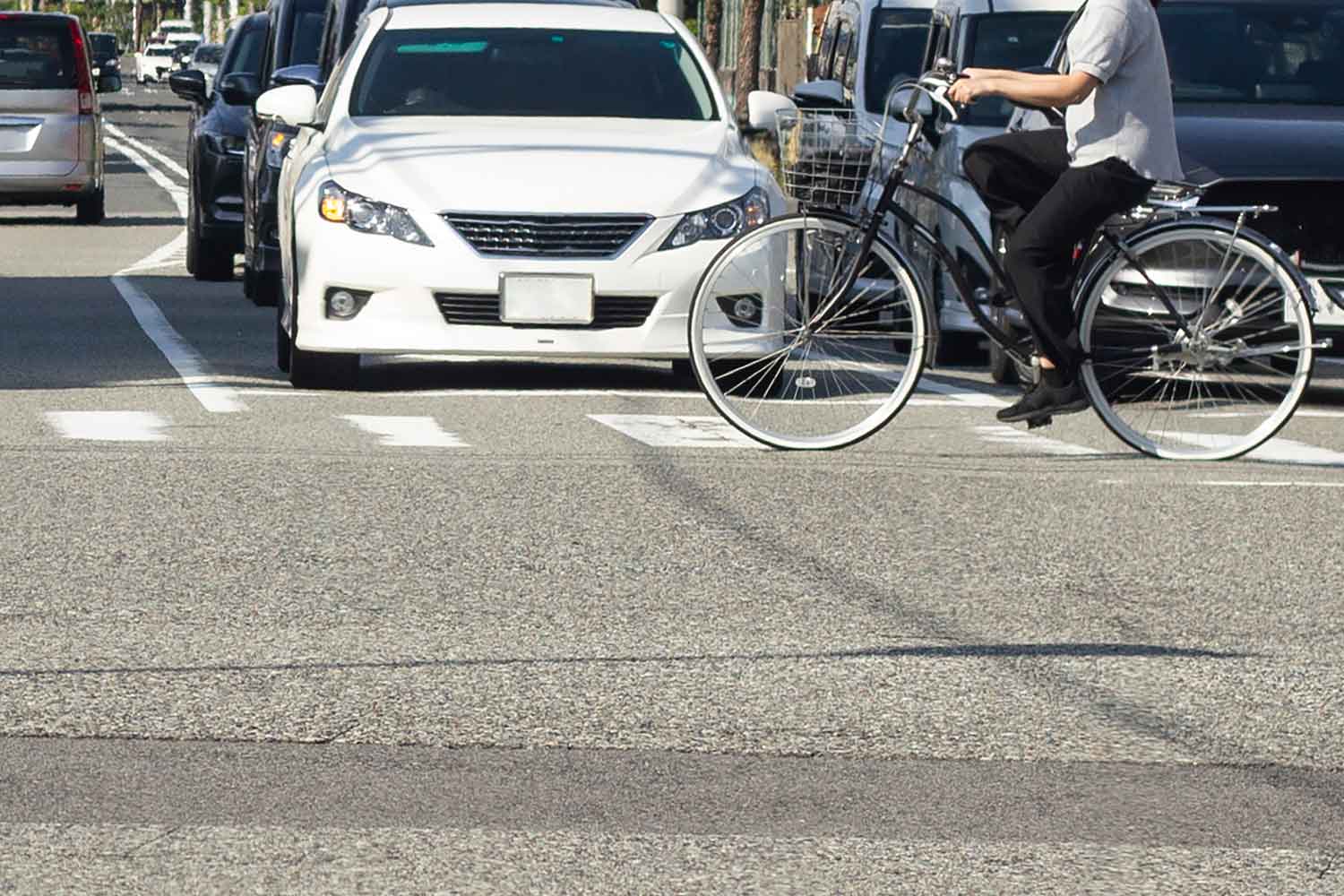 横断歩道を横断する自転車と信号待ちの車列