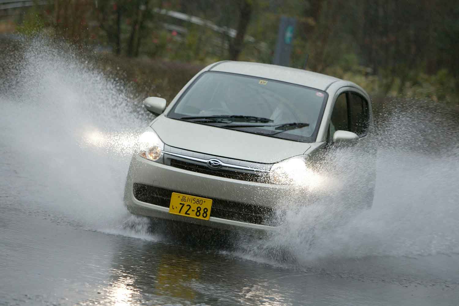 冠水した道路を走る軽自動車