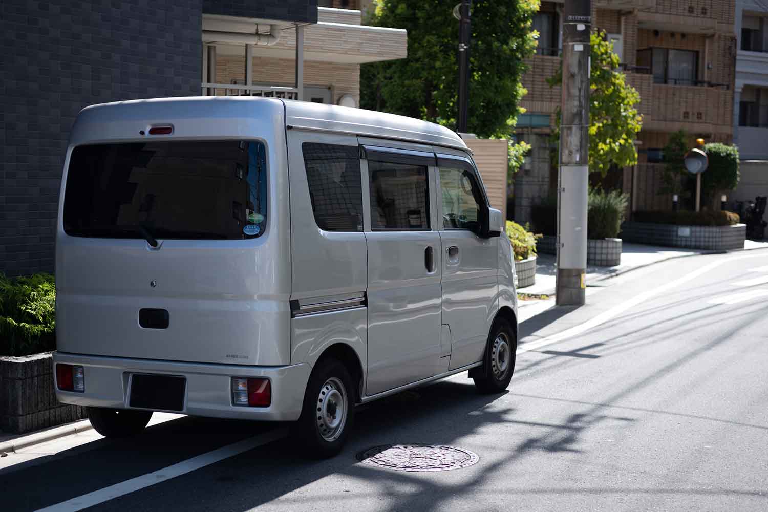 住宅街で停車している宅配の軽トラのイメージ