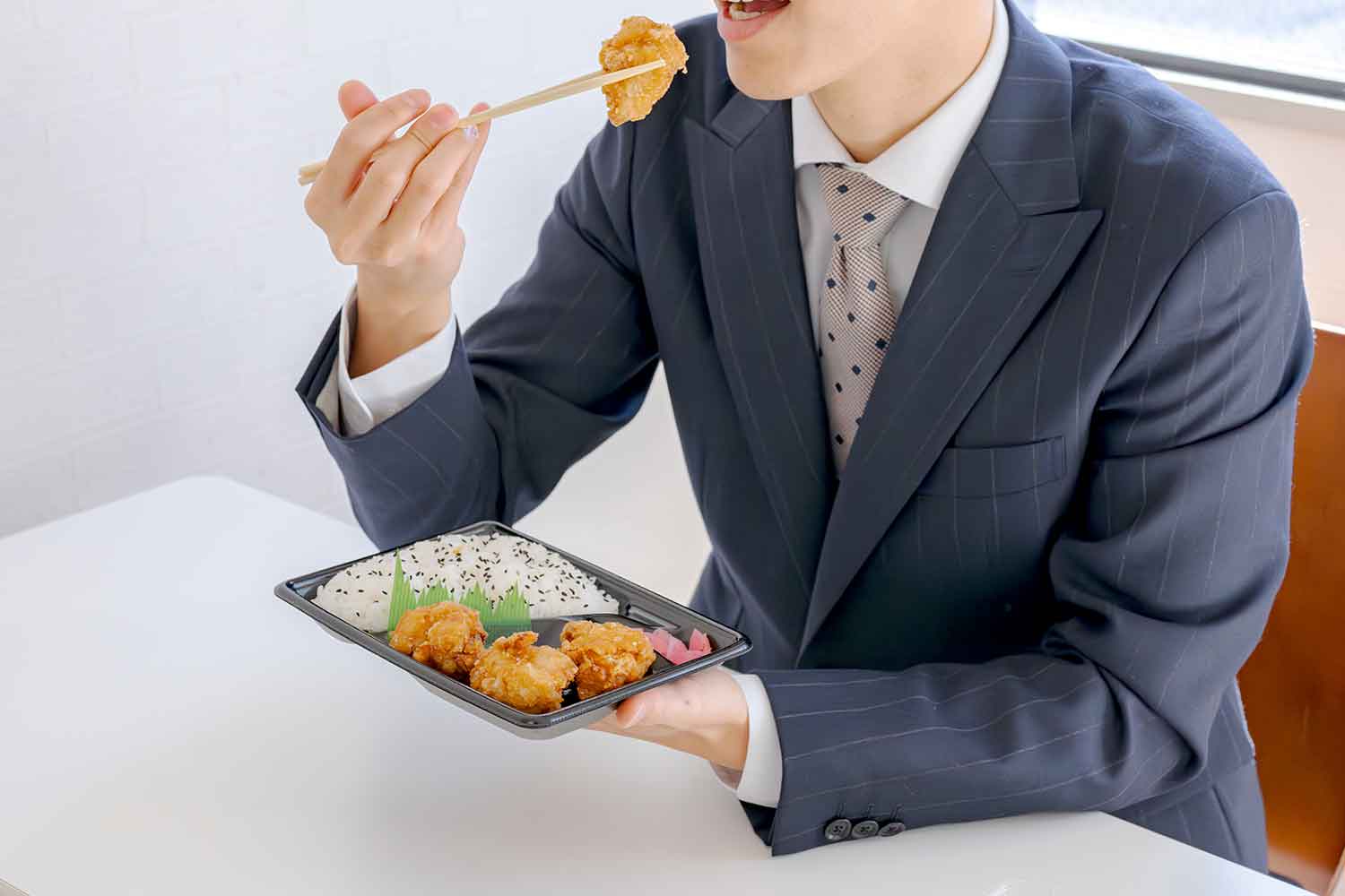 コンビニ弁当を食べている男性のイメージ