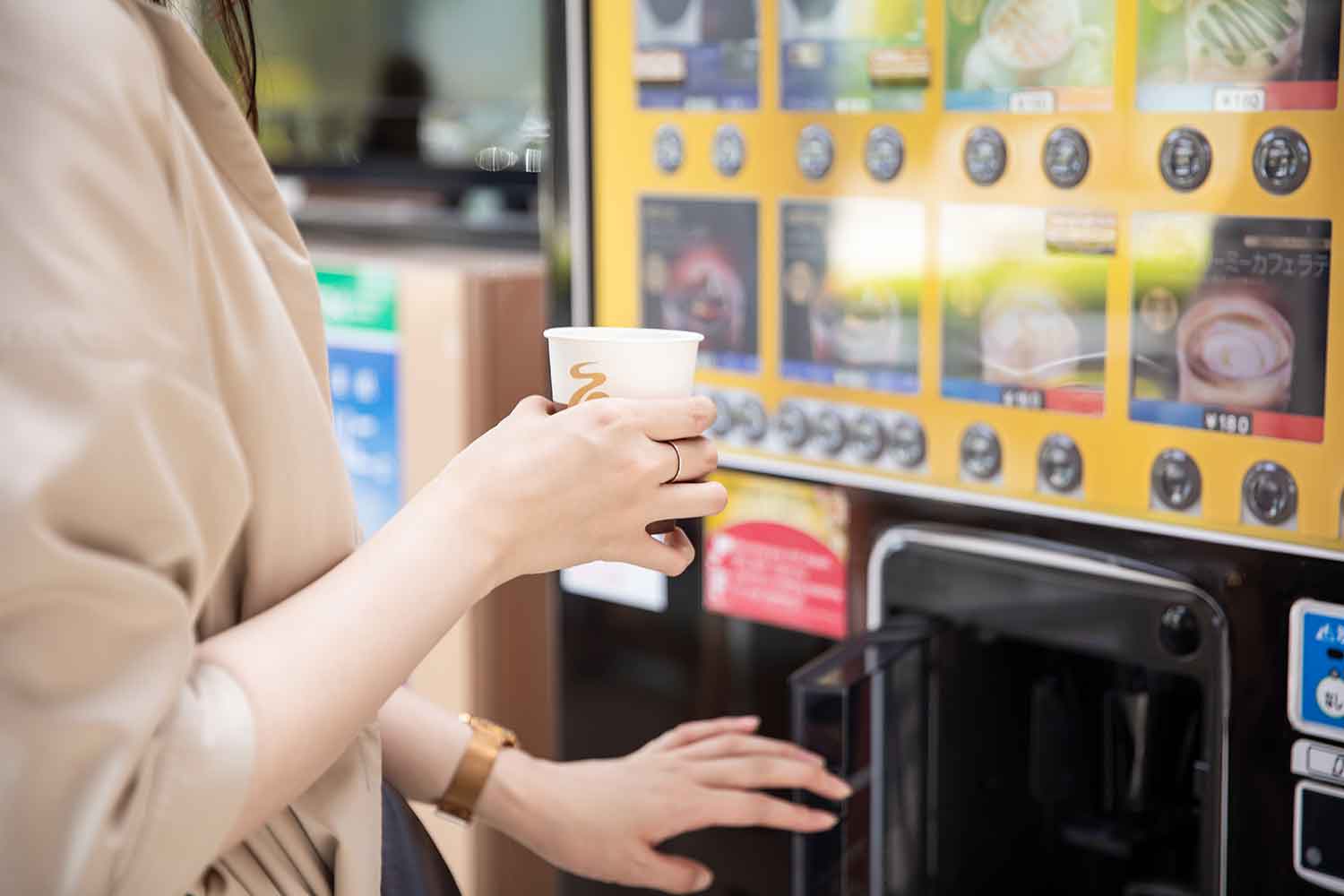 紙コップ式の自動販売機を利用する女性のイメージ