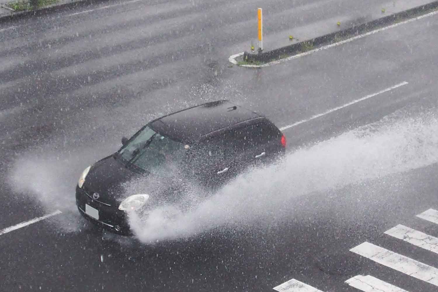 大雨が降っている道路を通行するクルマの様子