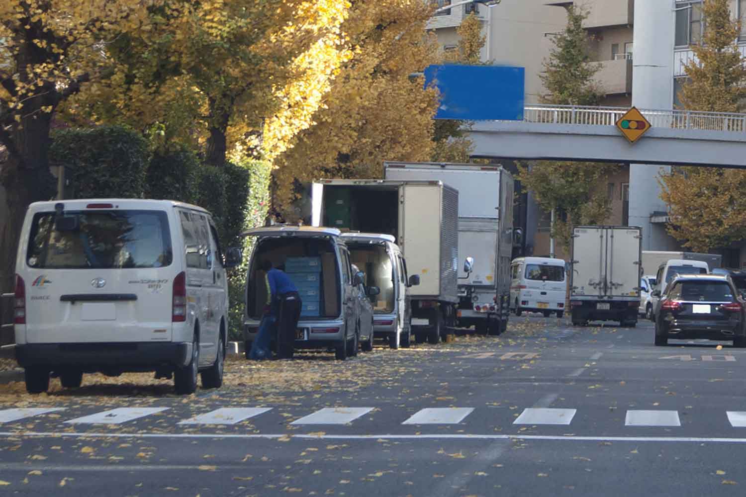 路肩で荷下ろしなどをしている貨物車両の様子