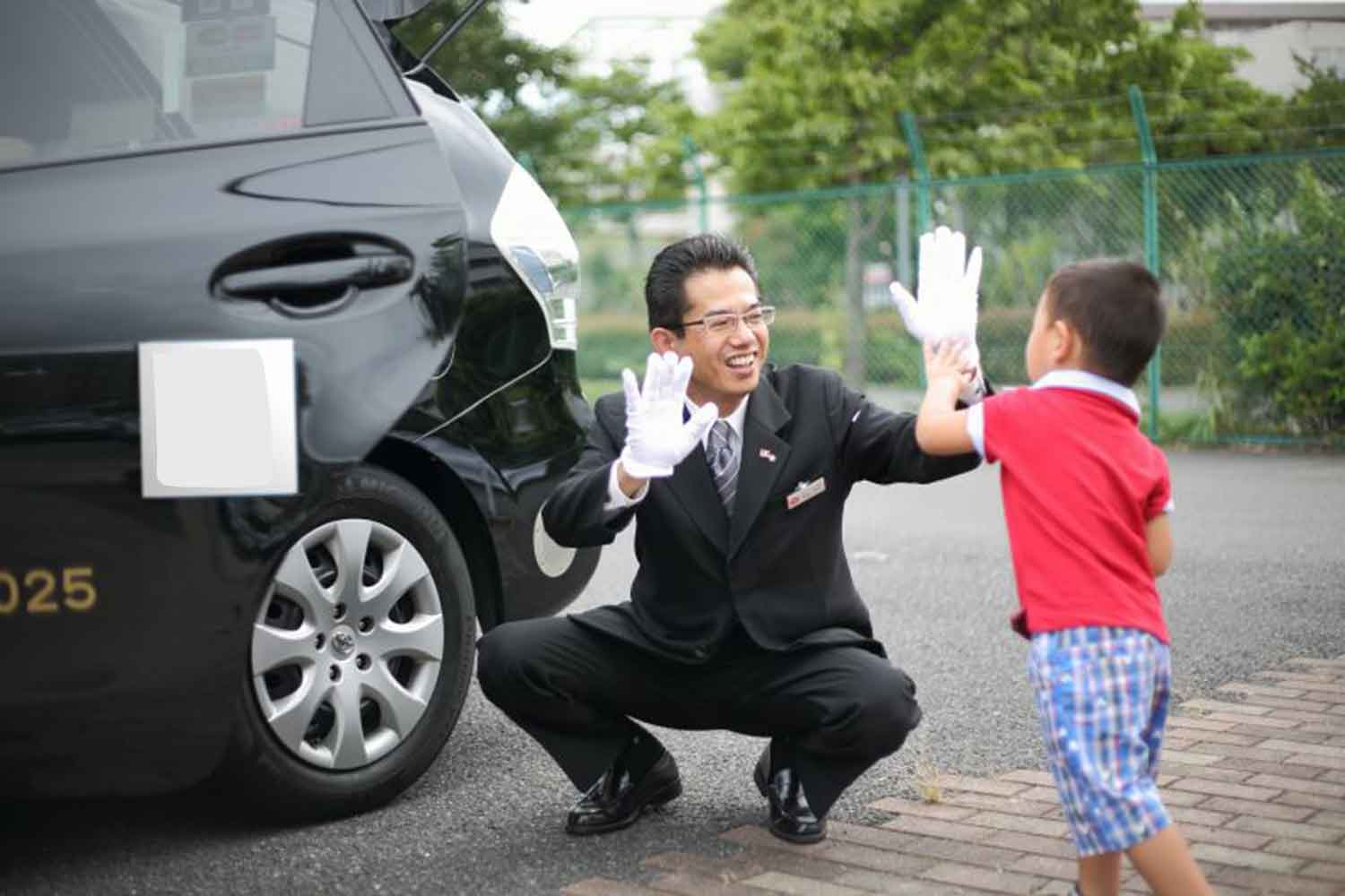 子どもとハイタッチする送迎担当のタクシー運転手