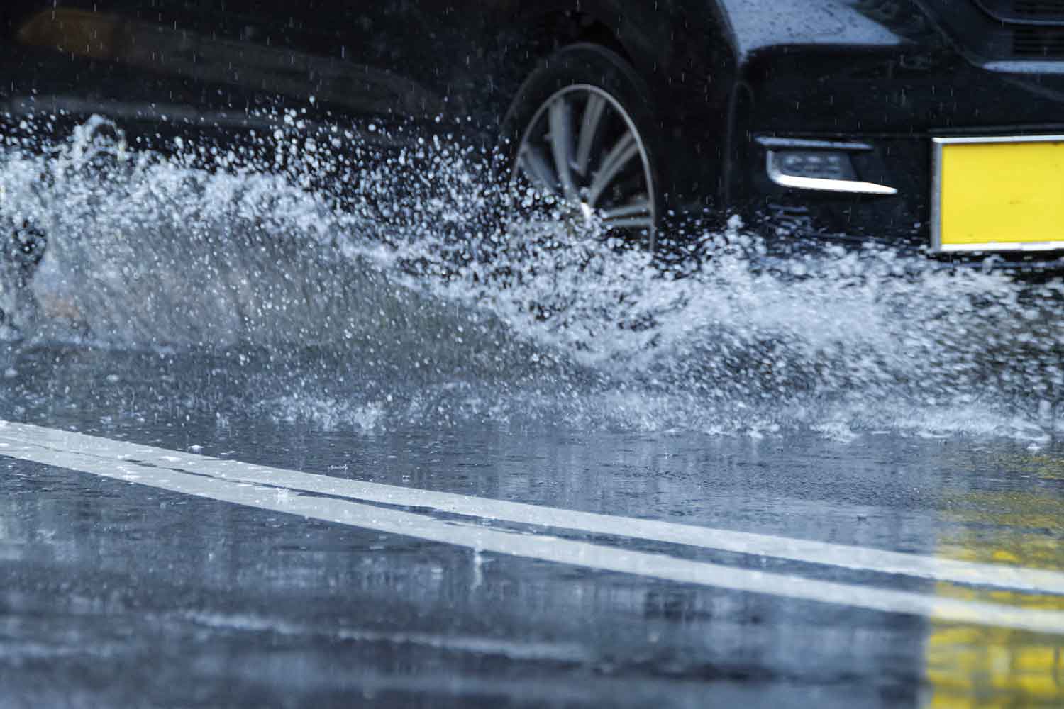 水しぶきを上げながら走る軽自動車のタイヤまわり