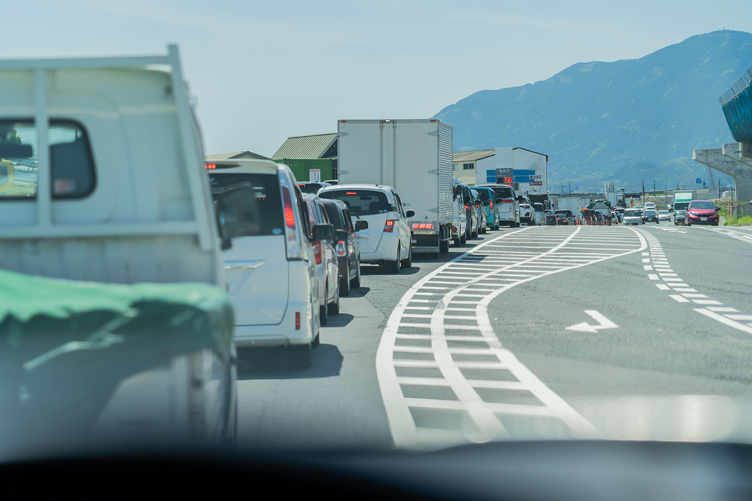 導流帯のある道路で信号待ちの車列ができている様子