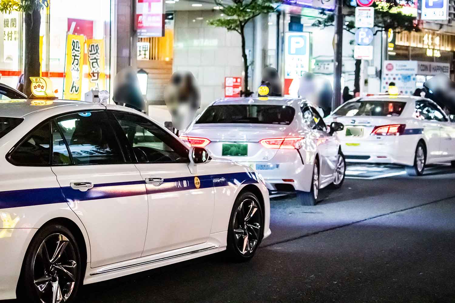 夜の繁華街で待機している個人タクシーの車列