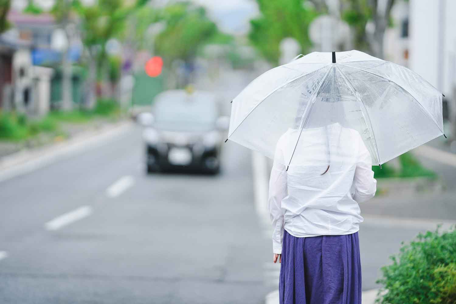 雨の日にタクシーを呼び止めようとしている様子