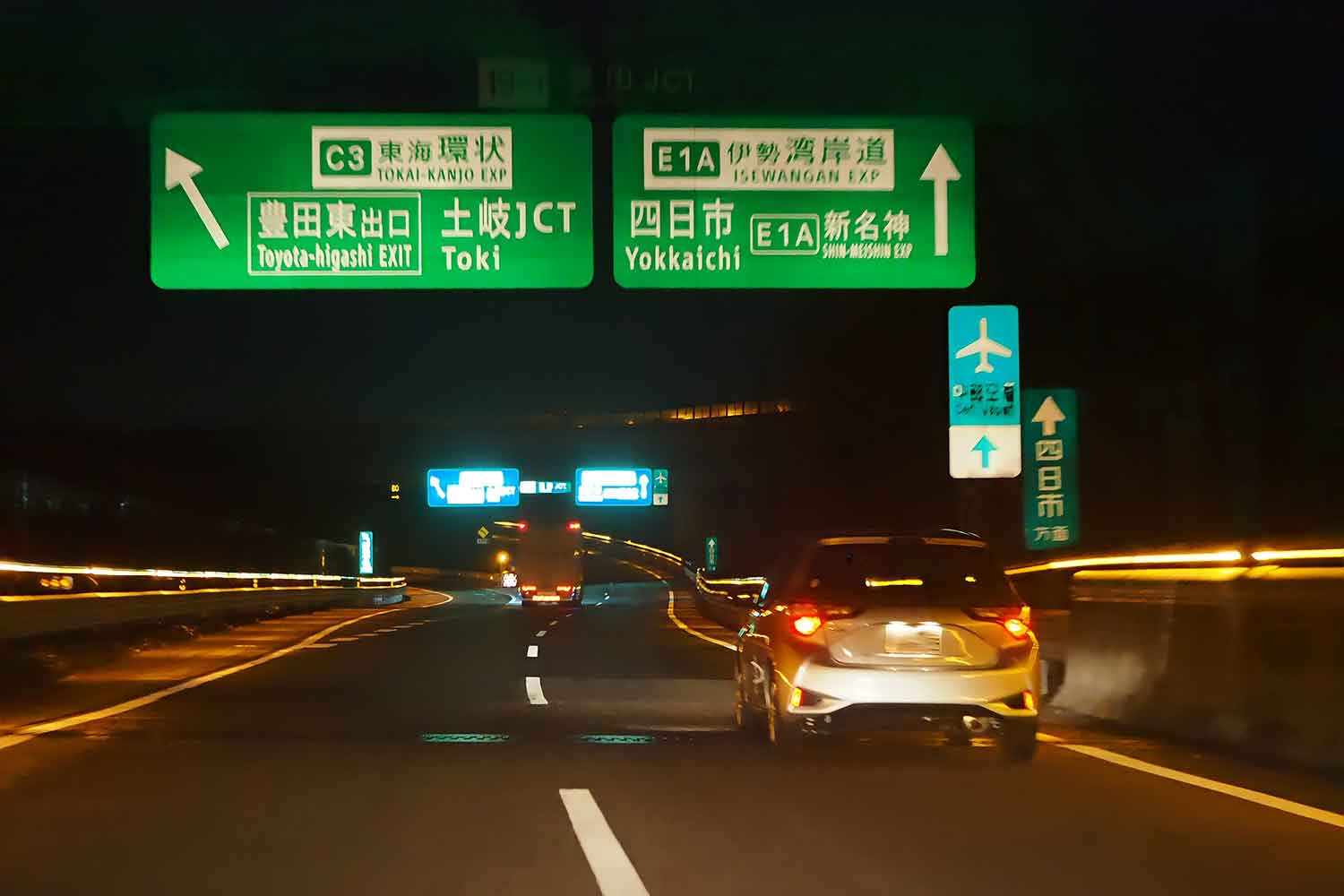 夜の高速道路の標識がライトで反射されている様子