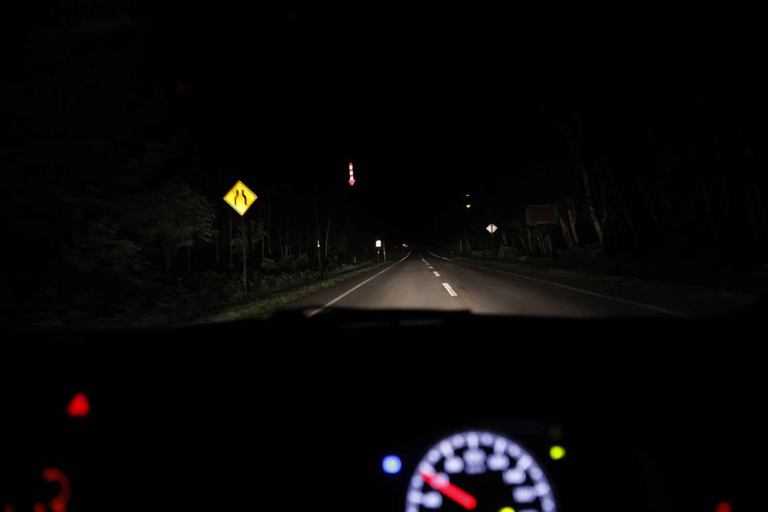 街灯のない夜道を走る車窓から見える道路標識