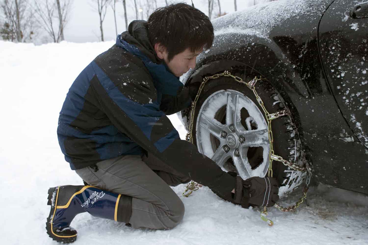 雪道でタイヤチェーンを装着している様子