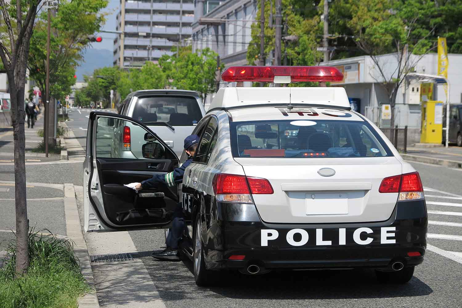 パトカーが路肩に違反車両を停車させている様子