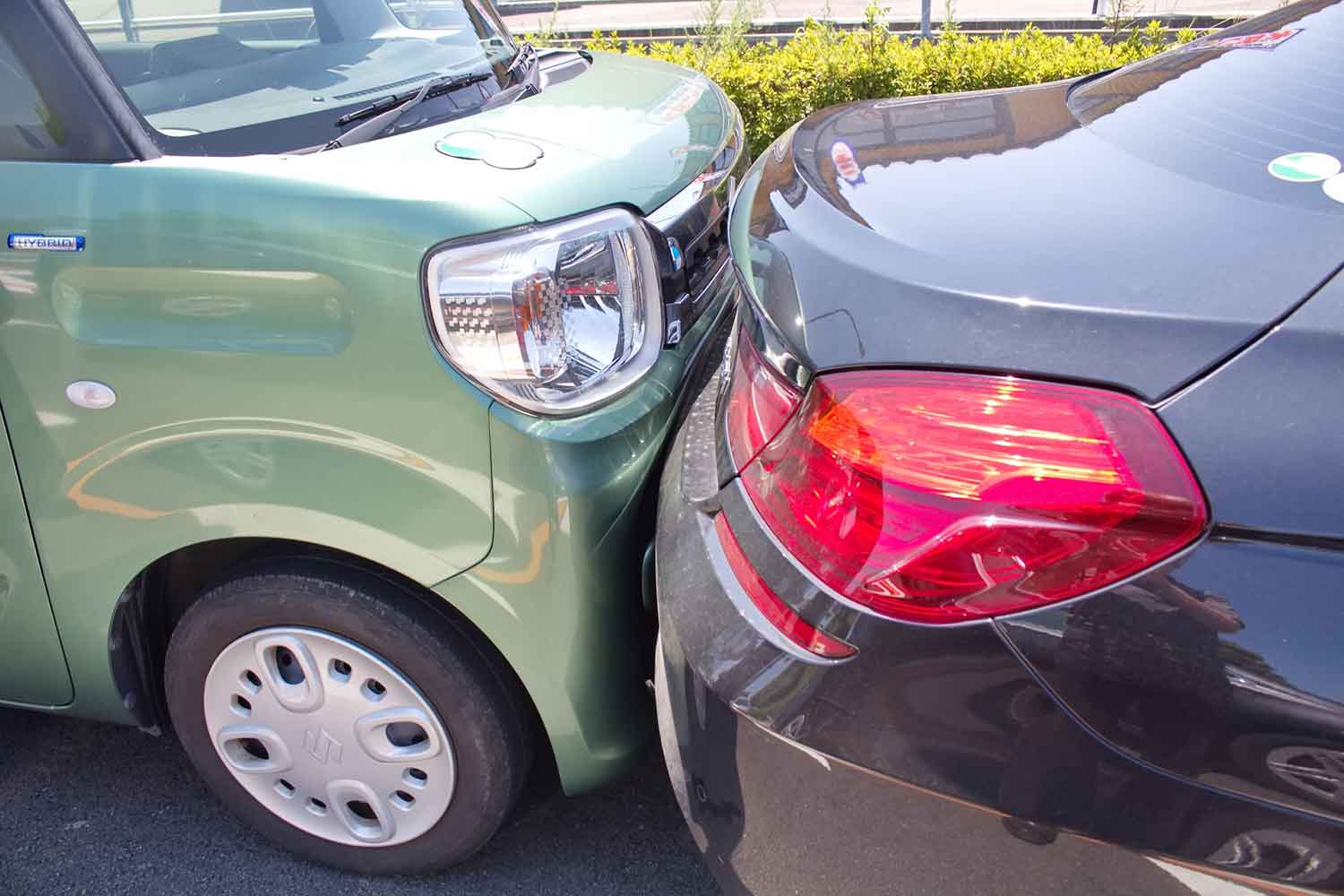 緑色の軽自動車が黒い高級車に追突している様子