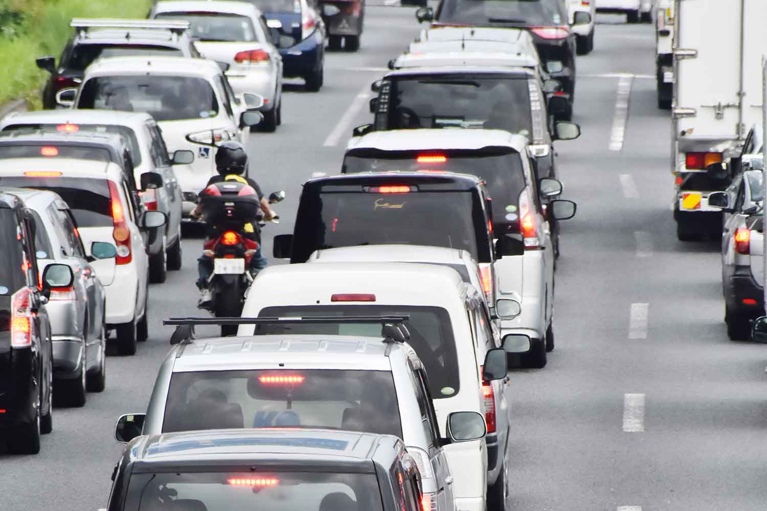 車列をすり抜けて通行しているバイクの後ろ姿