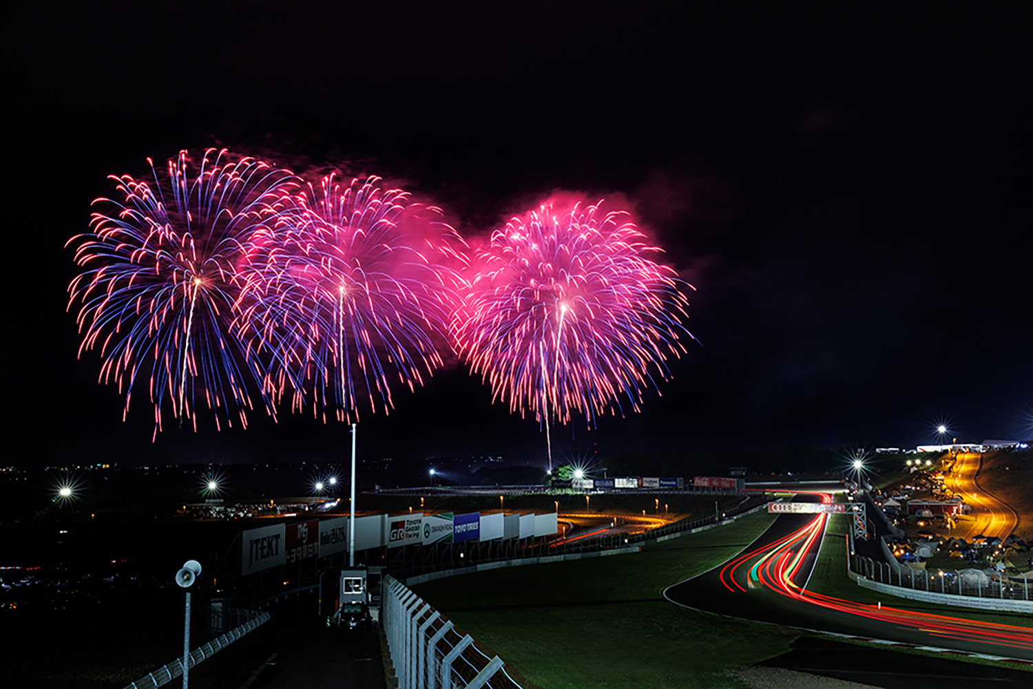 夜間走行するレースカーと打ち上げ花火