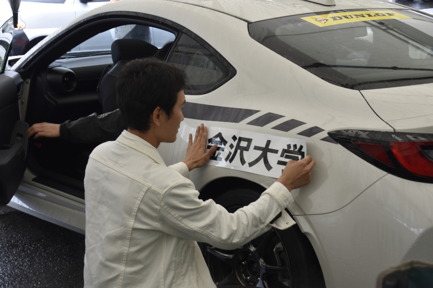 支給された「GR86」に大学名のステッカーを貼る学生