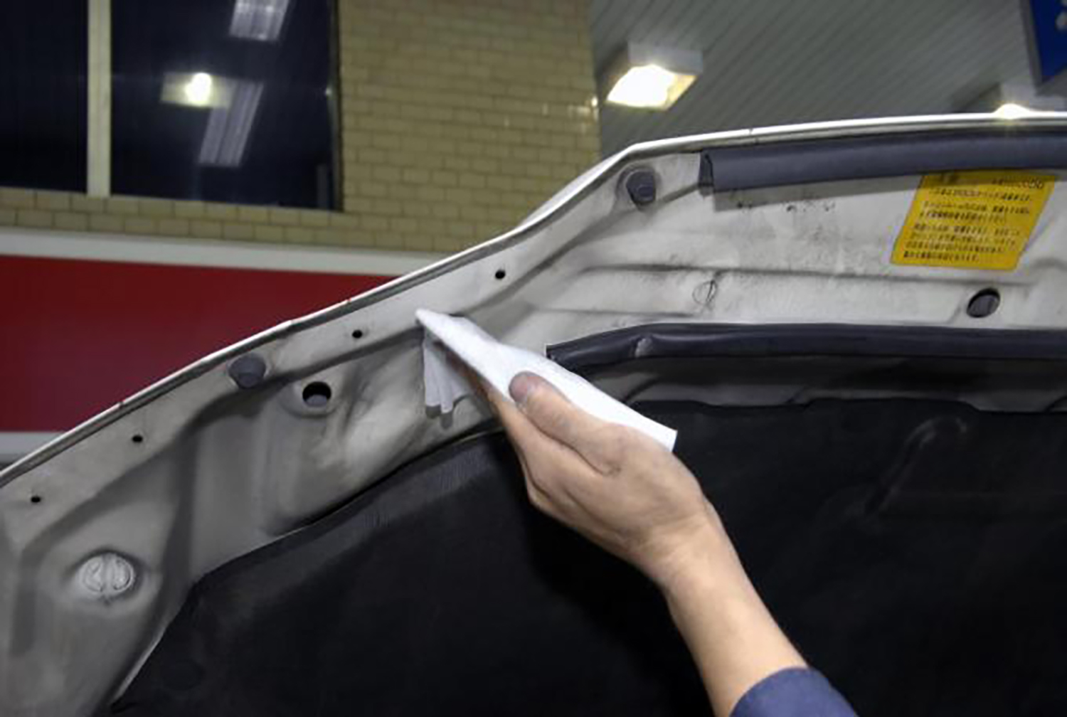 ボンネットの裏を掃除しているイメージ