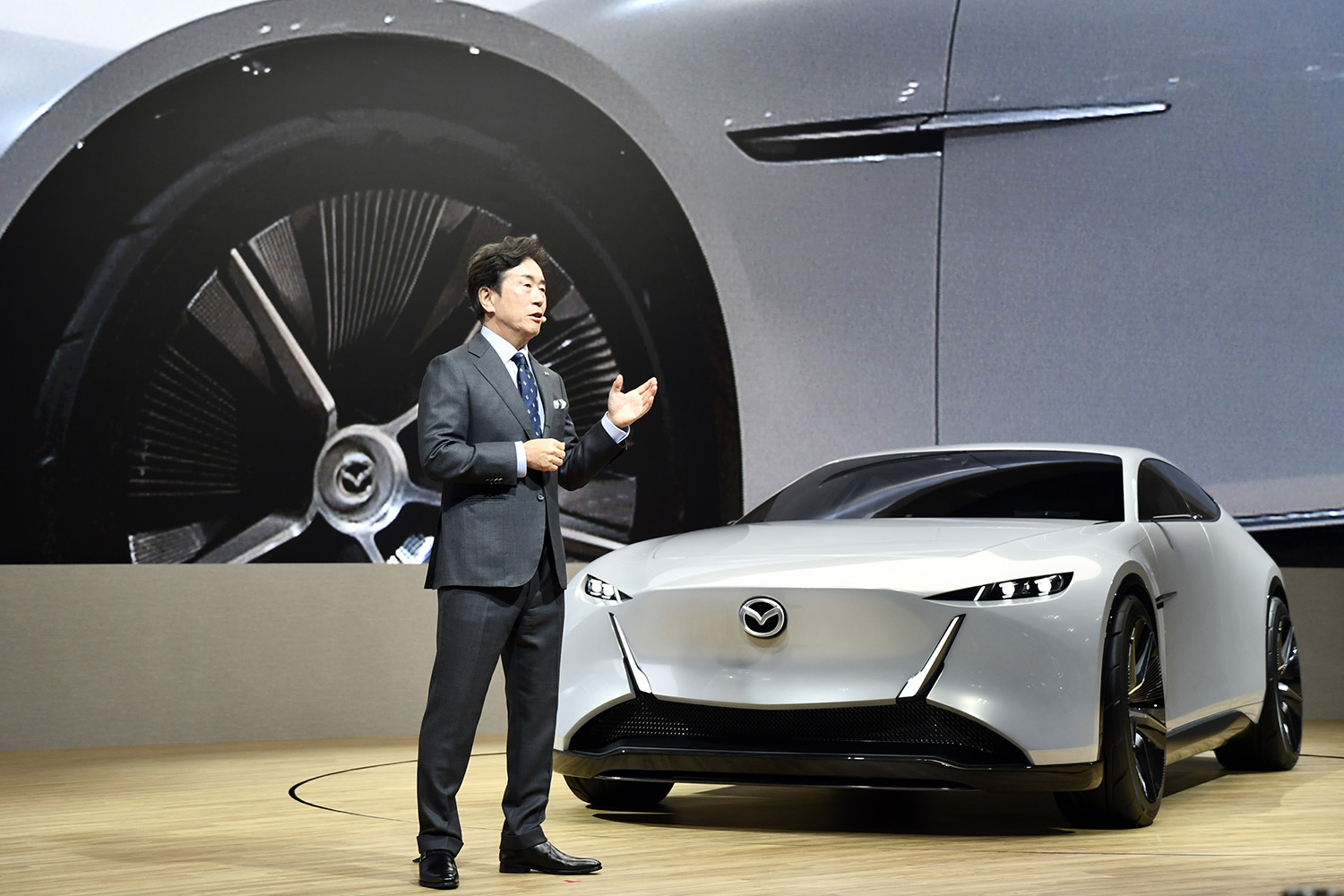 ジャパンモビリティショー2025でビジョンクロスクーペを発表するマツダの毛籠社長