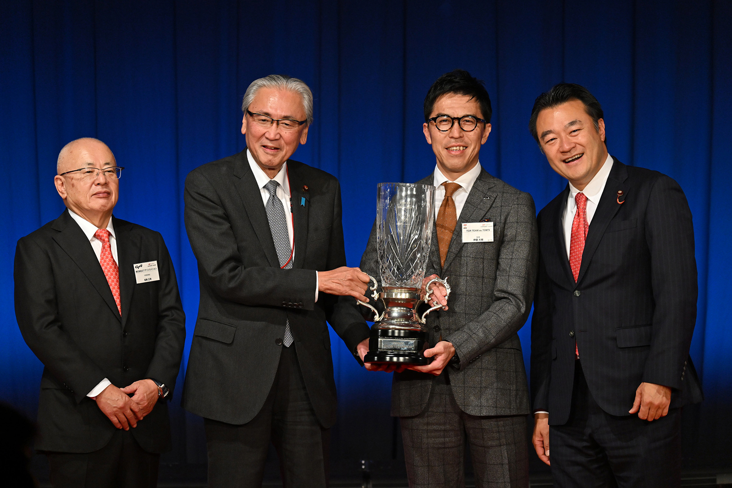 伊藤大輔監督にトロフィを手渡す自由民主党モータースポーツ振興議員連盟の古屋圭司会長