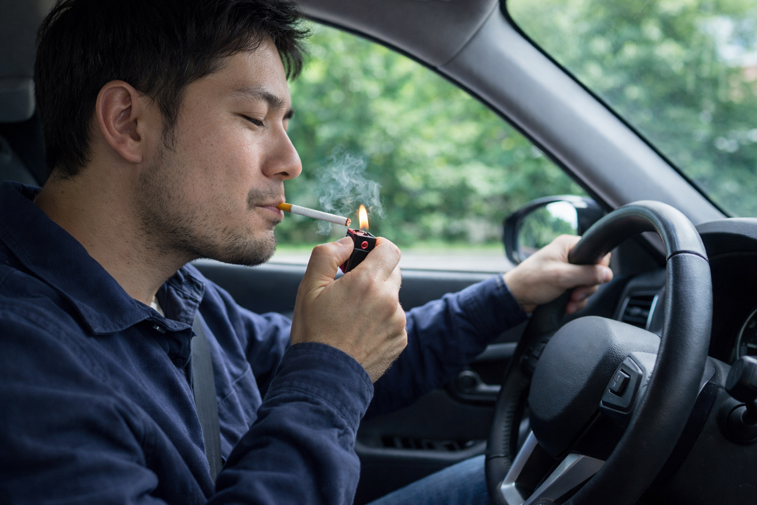 運転しながらタバコに火をつける男性