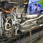 【画像】クルマが横倒しでマフラーまる見え！　フジツボブースの展示は技術力もまる見えだった【東京オートサロン2026】 〜 画像2