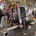 【画像】クルマが横倒しでマフラーまる見え！　フジツボブースの展示は技術力もまる見えだった【東京オートサロン2026】 〜 画像6