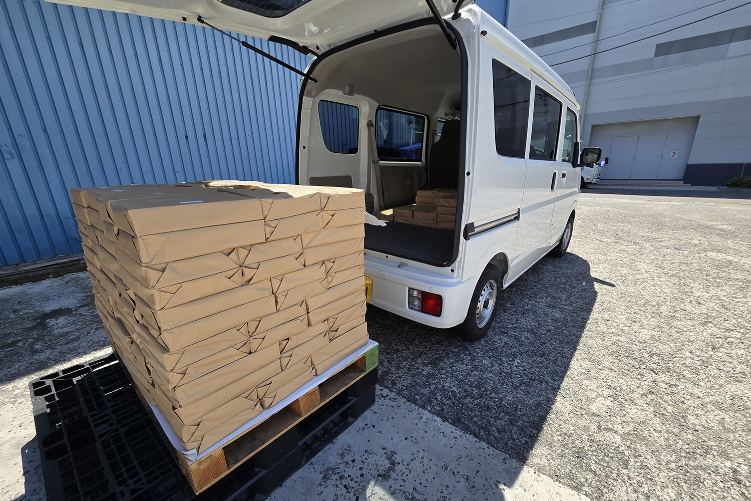 配送のために荷物を積み込む軽バン