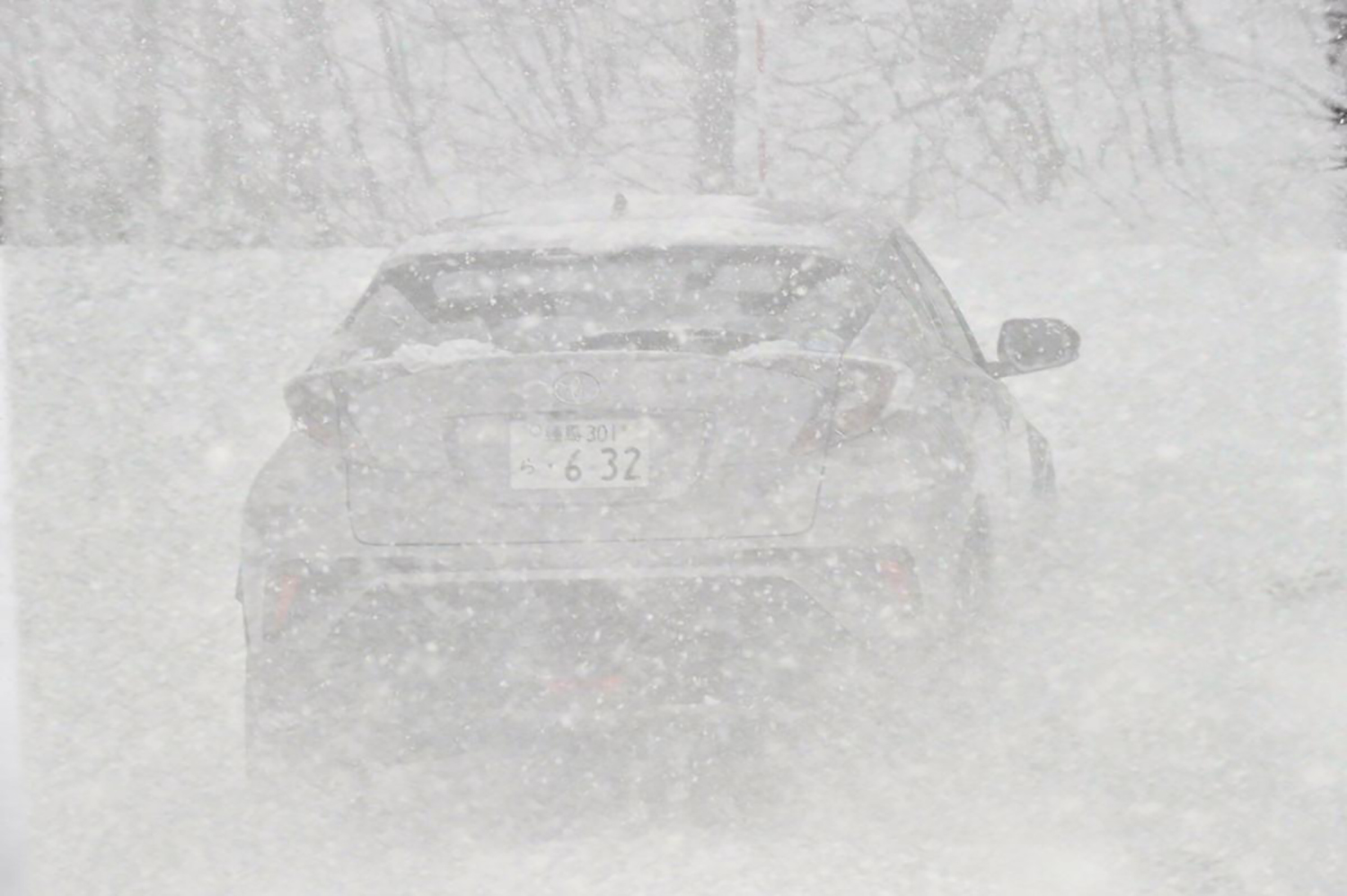 吹雪のなかを走るクルマのイメージ
