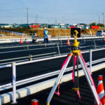 【画像】道路っぱたで技師が何か覗いている「測量」！　道路を守るためには必要不可欠な作業について解説!! 〜 画像1