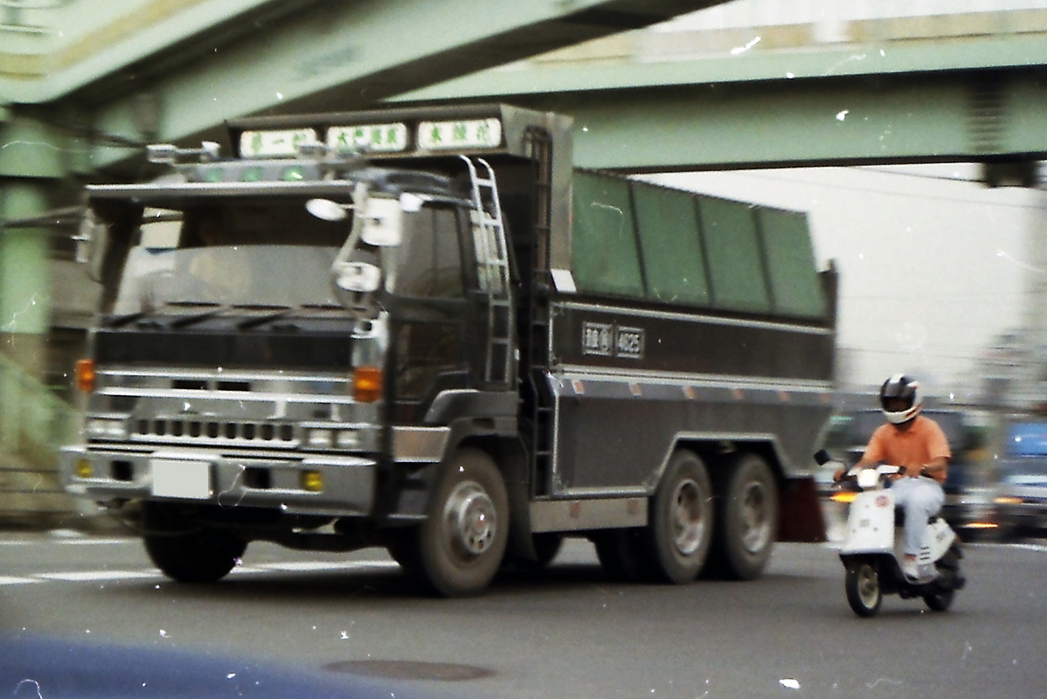 大型トラックと並走する原付バイク